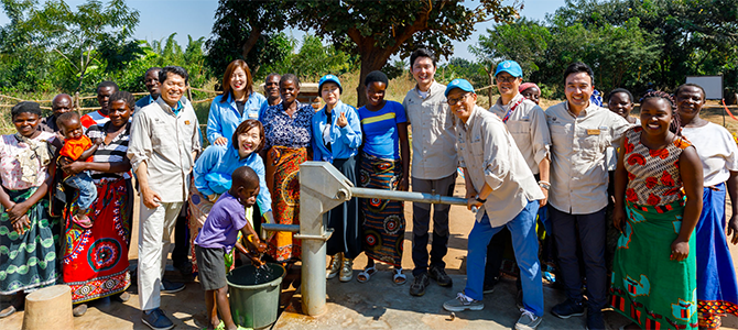 Nu Skin sales leaders and employees pose for a picture with locals from the village of Kasiya as they dedicate a new borehole water well to their village.