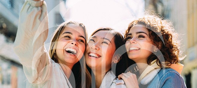 three girls taking a selfie with Nu Skin logo overlay