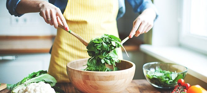 person tossing a leafy green salad