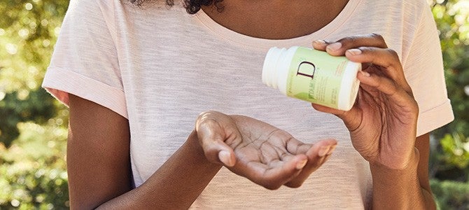 black woman holding a bottle of Pharmanex Vitamin D3