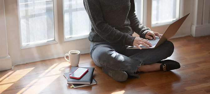 person sitting on the floor working on their laptop