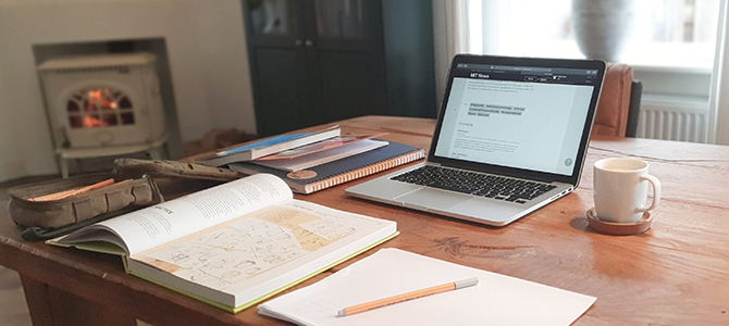 organized desk with laptop, books, and a notebook