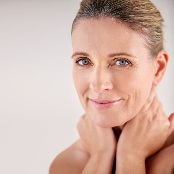 Middle-aged female resting hands on her neck while smiling after selecting superior supplements