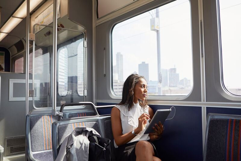 Businesswoman heading home from work on public transit while working on a tablet