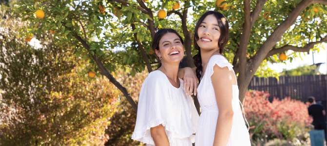 Two women under a fruit tree smiling about Nu Skin Beauty Focus™ Collagen+