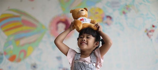 Yu-Jie smiles as she plays with a teddy bear.