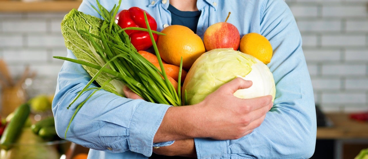 Hình ảnh người đàn ông đang ôm các loại hoa quả đầy dinh dưỡng